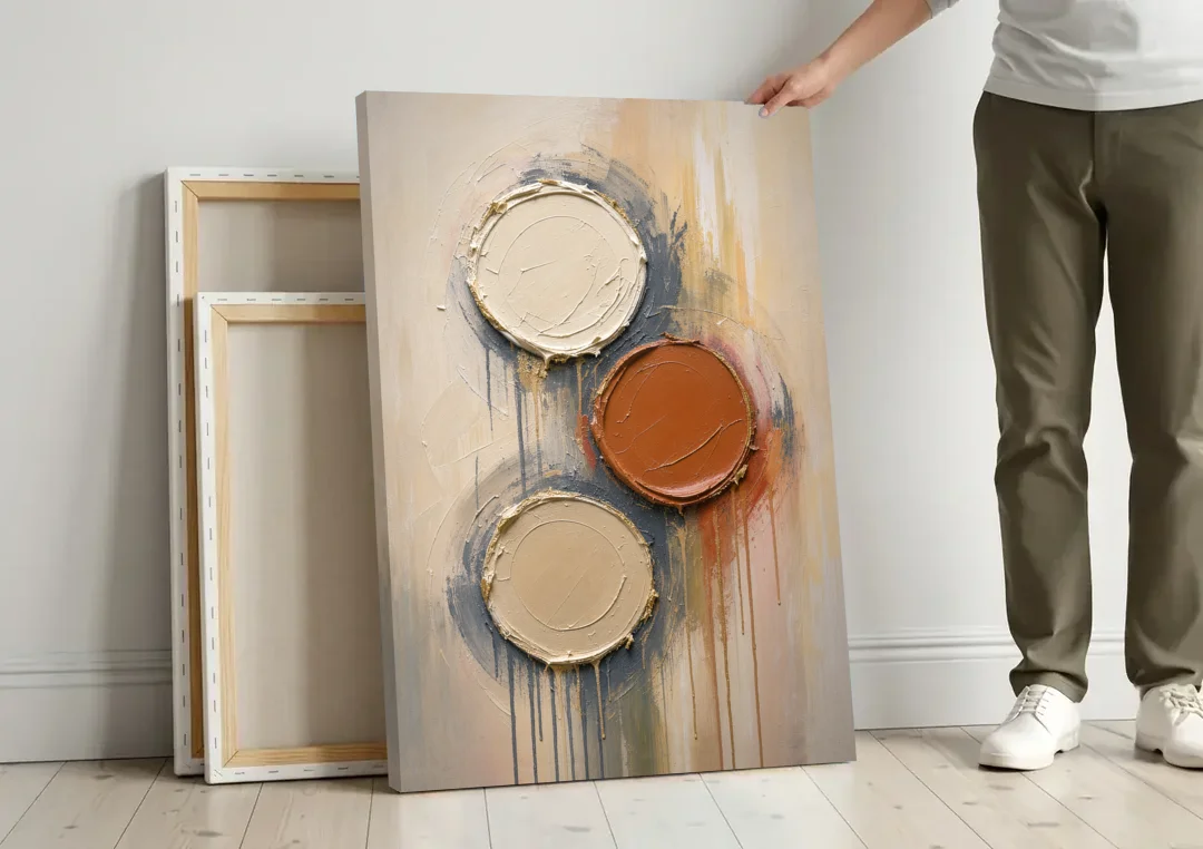 3D Textured Terracotta Disc Trio canvas wall art leaning against a wall next to blank canvases