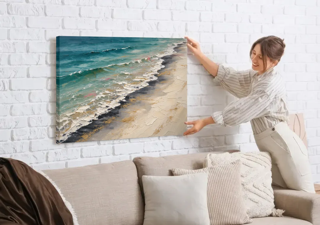 Abstract Beach Painting with Gold Foam Lines canvas wall art being hung on a white brick wall above a sofa
