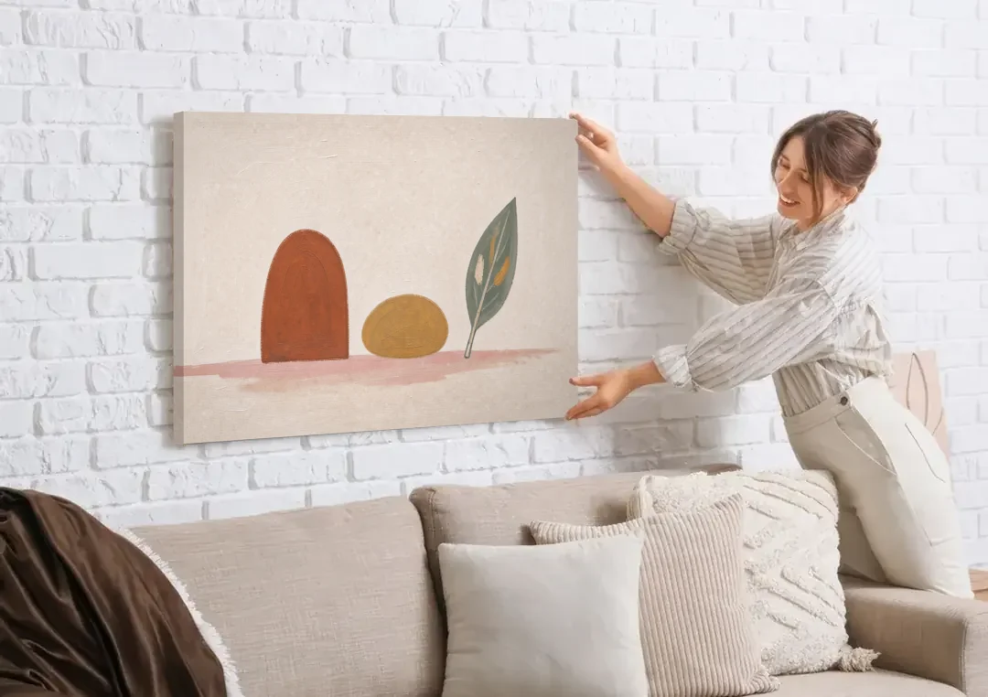 Abstract Shapes Wall Art with Arch, Pebble and Leaf canvas wall art being hung on a white brick wall above a sofa
