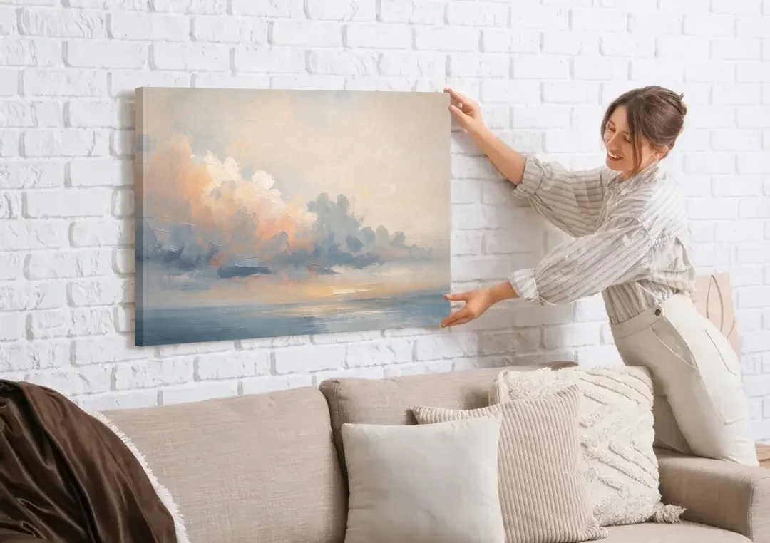 Abstract Sky Painting with Peach Cloud Bank canvas wall art being hung on a white brick wall above a sofa