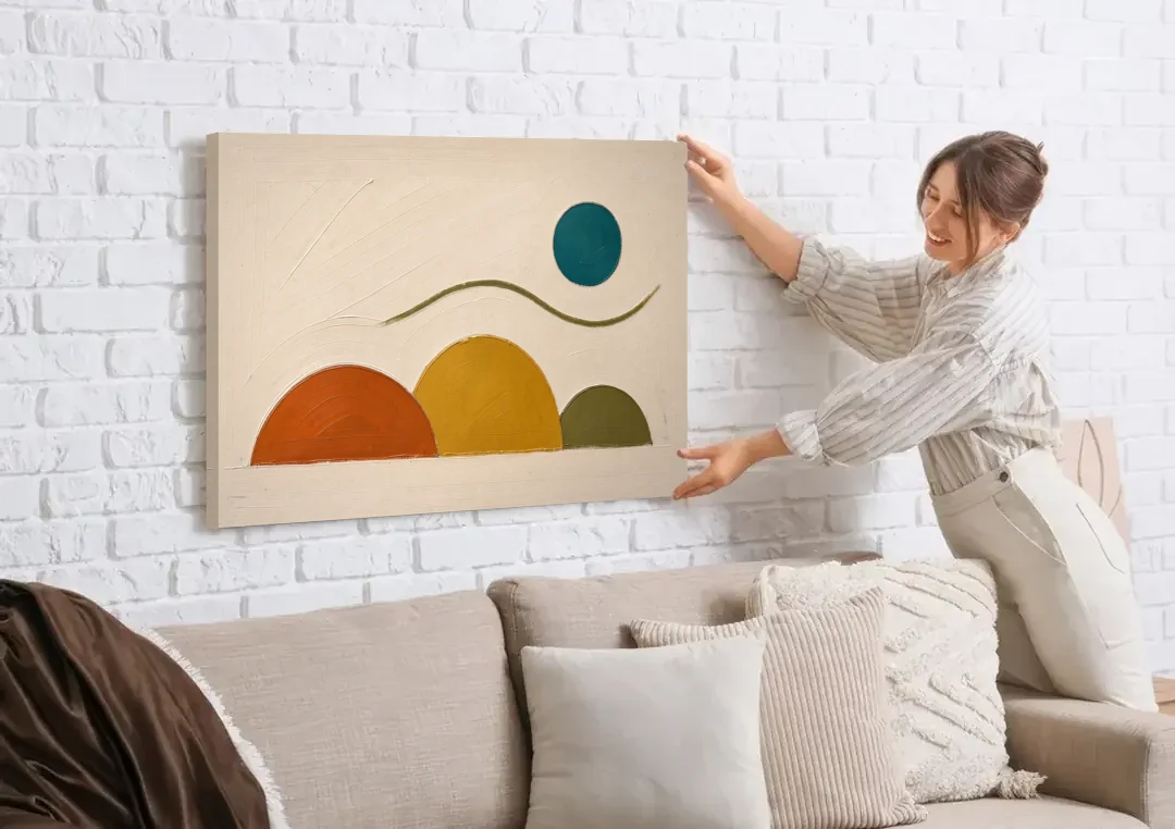 Abstract Wall Art for Living Room with Teal Sun canvas wall art being hung on a white brick wall above a sofa