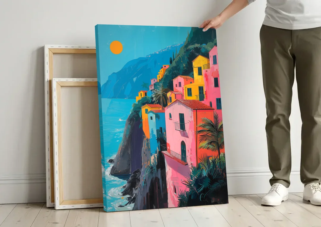 Amalfi Painting of Pink Cliff Houses canvas wall art leaning against a wall next to blank canvases