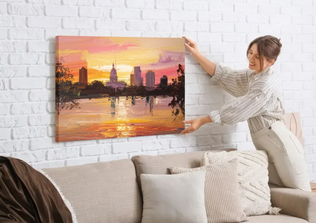 Baton Rouge Skyline Sunset canvas wall art being hung on a white brick wall above a sofa
