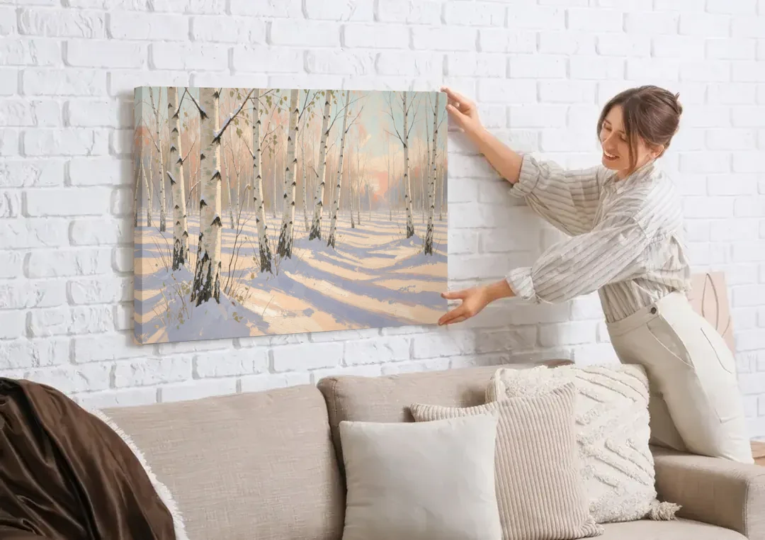 Birch Forest Painting in Morning Snow canvas wall art being hung on a white brick wall above a sofa