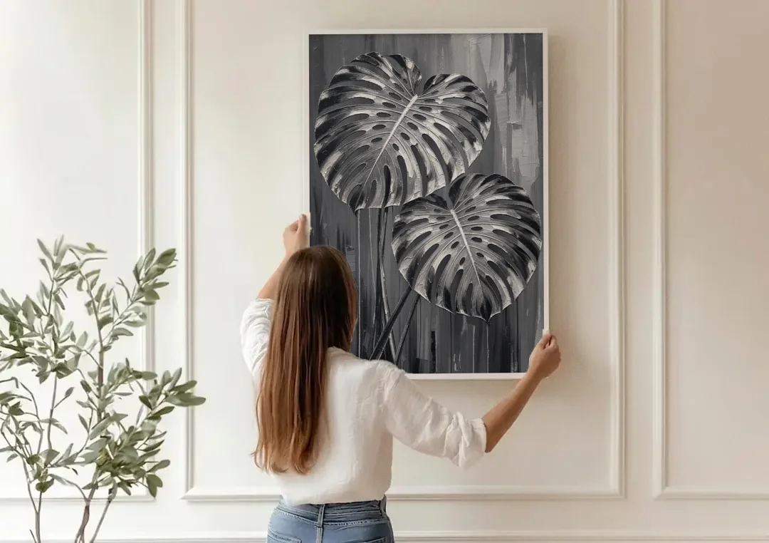 Black and White Botanical Prints Monstera Leaves canvas wall art being hung on a paneled wall