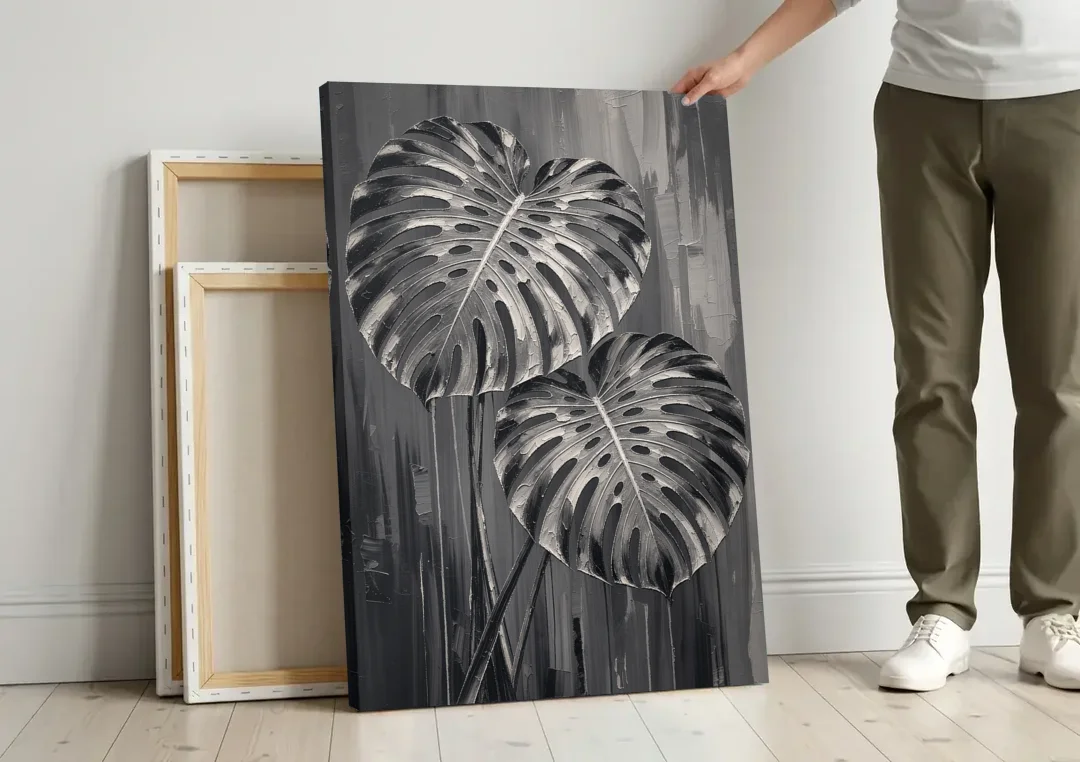 Black and White Botanical Prints Monstera Leaves canvas wall art leaning against a wall next to blank canvases