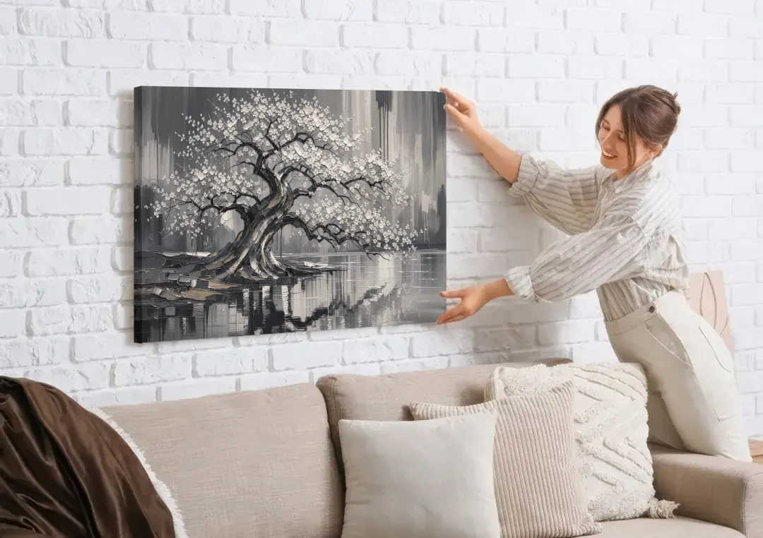 Black and White Cherry Blossom Over a Still Pond canvas wall art being hung on a white brick wall above a sofa