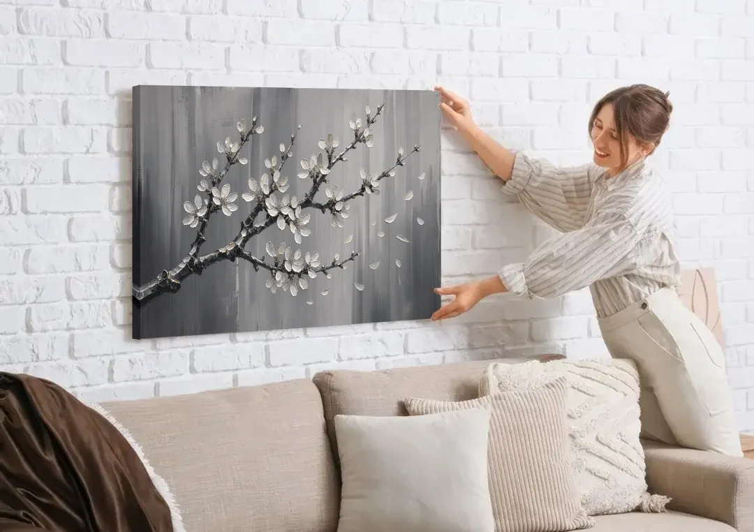 Black and White Cherry Blossom Painting with Drifting Petals canvas wall art being hung on a white brick wall above a sofa