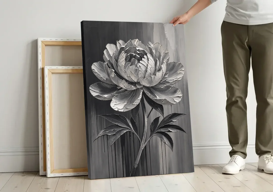 Black and White Flower Painting of a Peony canvas wall art leaning against a wall next to blank canvases