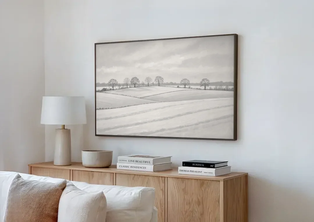 Black and White Landscape Painting of Snowy Fields canvas wall art above a wooden sideboard next to a sofa