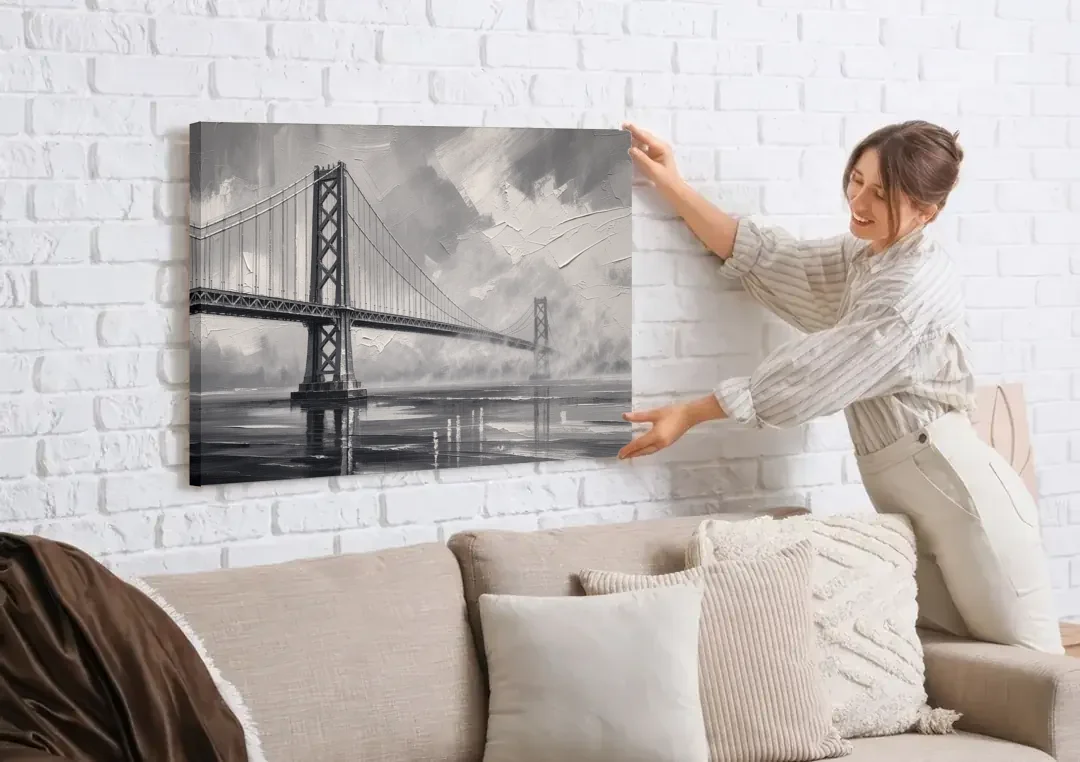 Black and White Panoramic Wall Art of a Bridge canvas wall art being hung on a white brick wall above a sofa