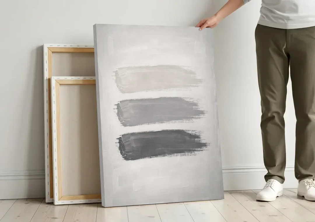 Black and White Stacked Brush Stroke Trio canvas wall art leaning against a wall next to blank canvases