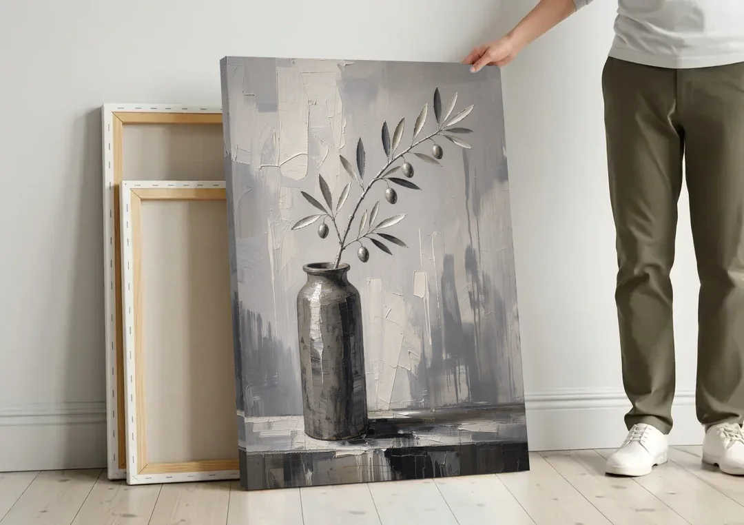 Black and White Vase Painting with Olive Branch canvas wall art leaning against a wall next to blank canvases