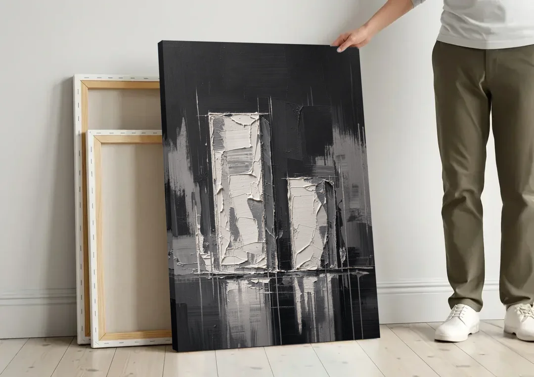 Black Minimalist Wall Art of Tall and Short Blocks canvas wall art leaning against a wall next to blank canvases