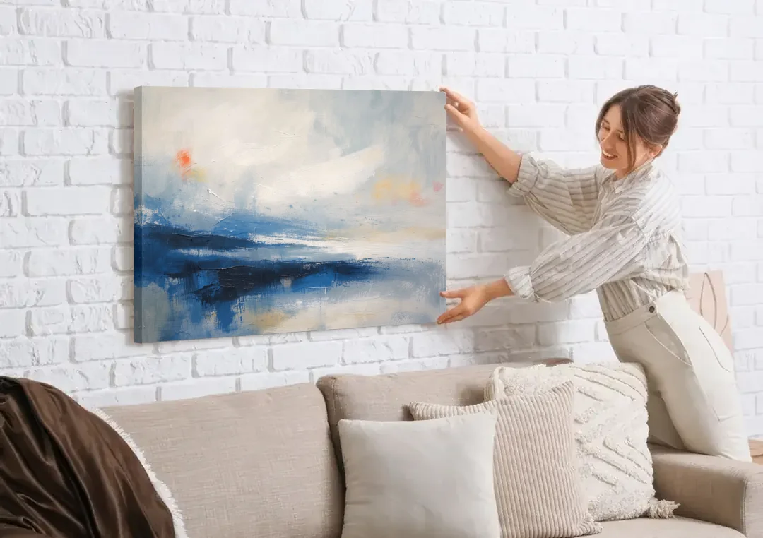 Blue and White Abstract Painting of Tidal Mist canvas wall art being hung on a white brick wall above a sofa