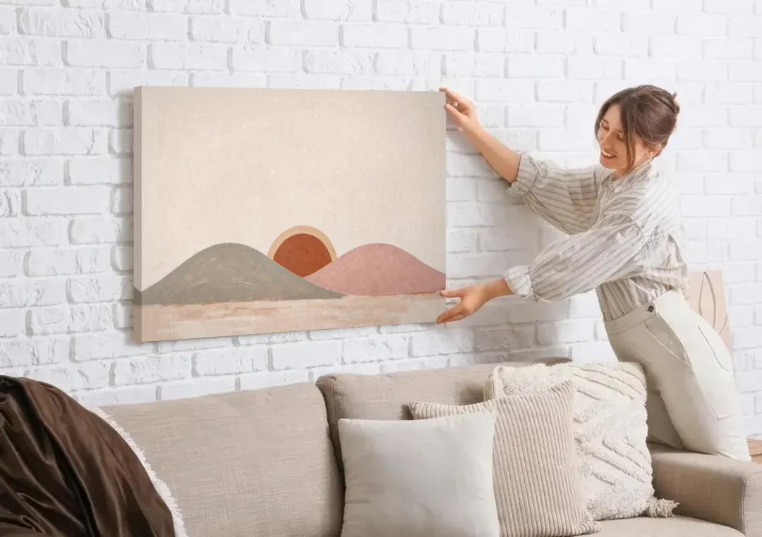 Boho Landscape Painting with Sun Between Hills canvas wall art being hung on a white brick wall above a sofa