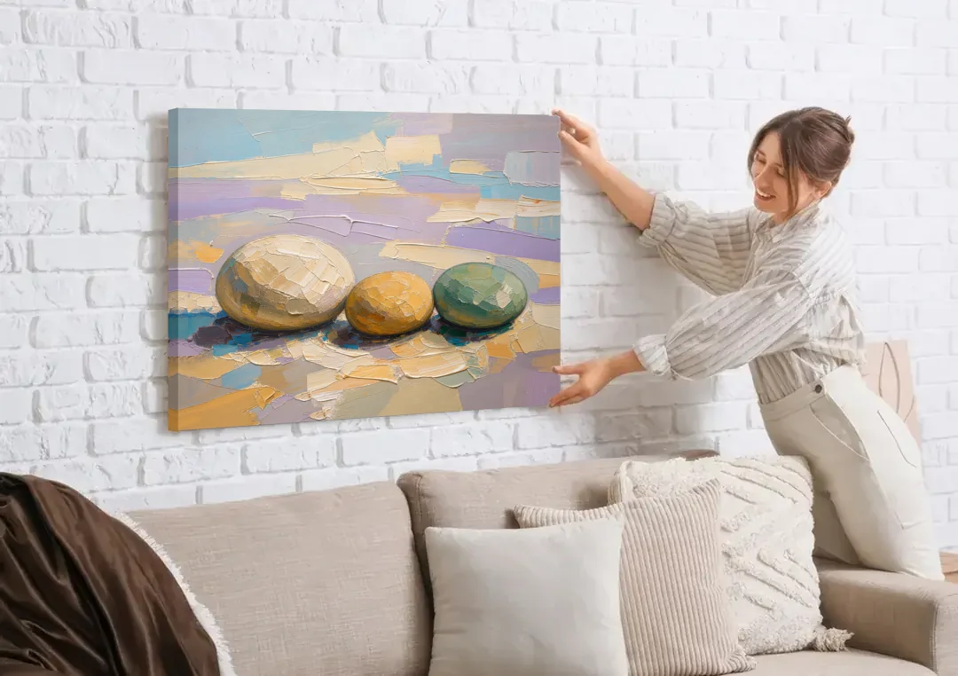 Boho Neutral Pebble Trio in Ivory, Ochre and Sage canvas wall art being hung on a white brick wall above a sofa