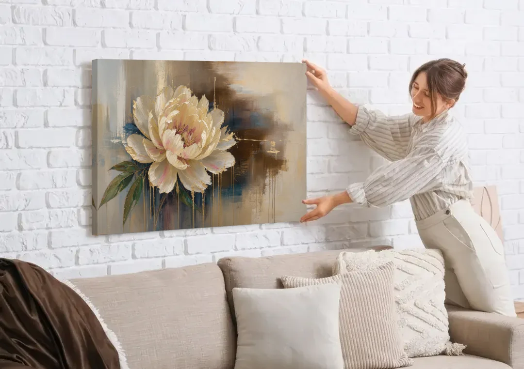 Brown Flower Wall Art with a Gilded Ivory Peony canvas wall art being hung on a white brick wall above a sofa
