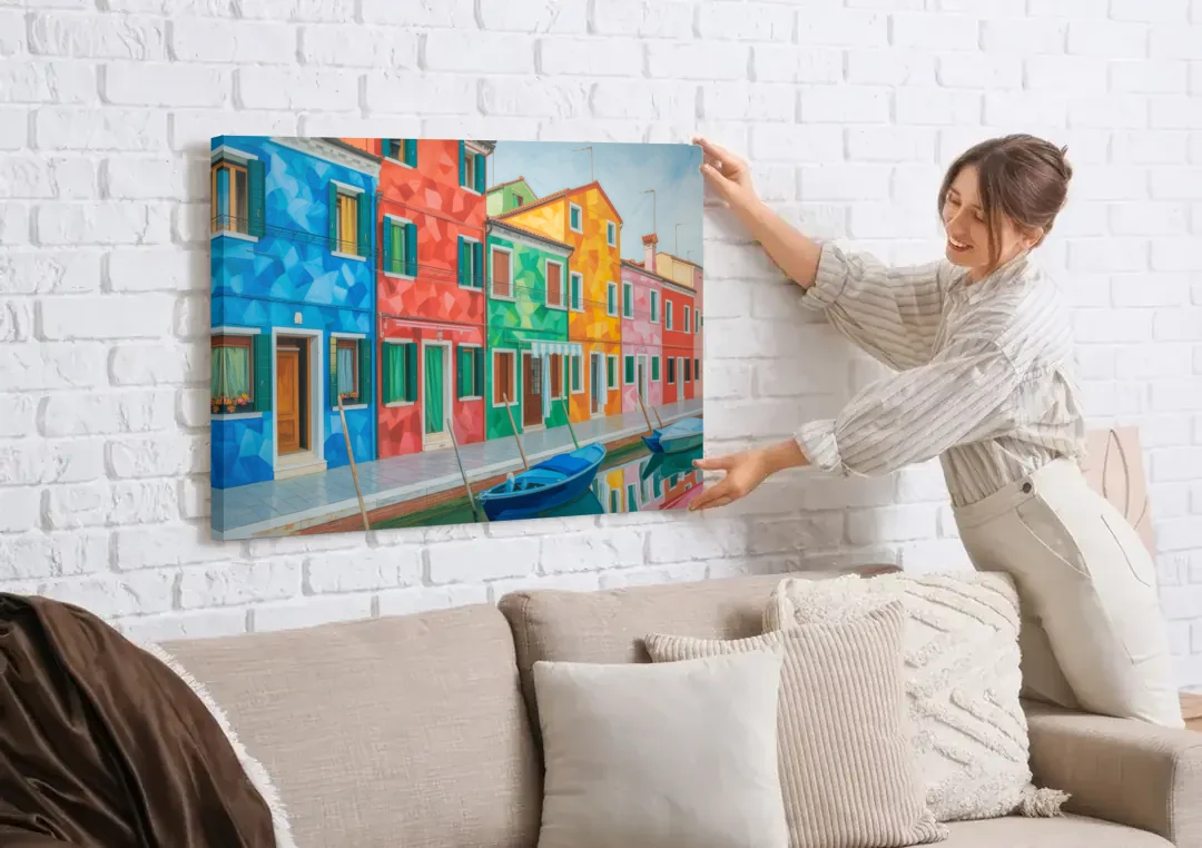 Burano's Colorful Streets canvas wall art being hung on a white brick wall above a sofa