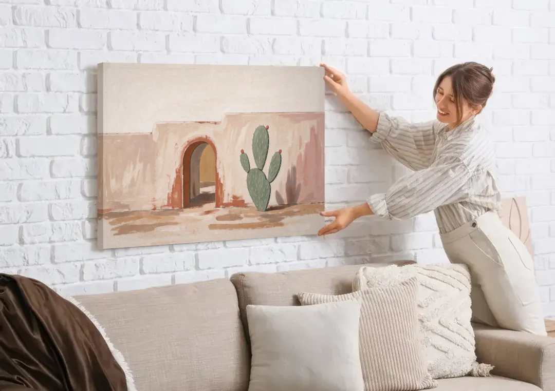 Cactus Wall Art by an Adobe Arch canvas wall art being hung on a white brick wall above a sofa