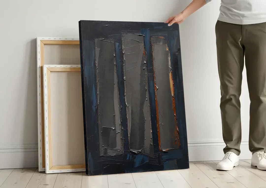 Charcoal Abstract Painting of Three Monoliths canvas wall art leaning against a wall next to blank canvases