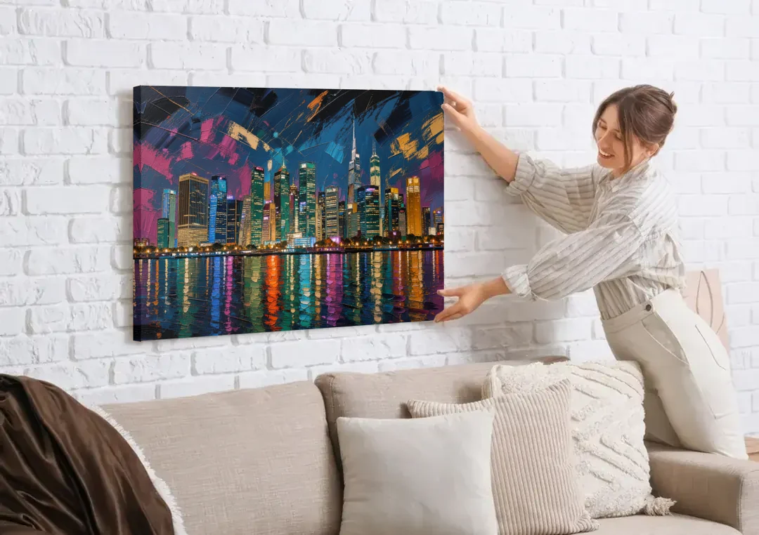 City at Night Painting Along the River canvas wall art being hung on a white brick wall above a sofa