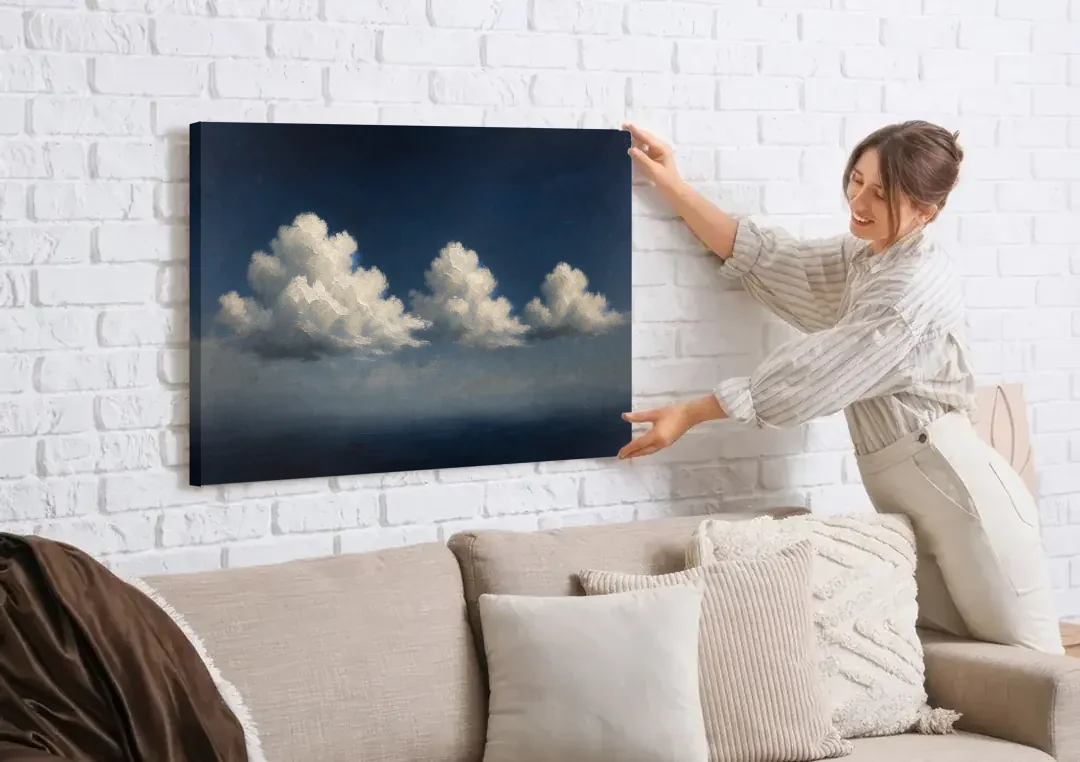 Cloud Wall Art with Three Moonlit Cumulus canvas wall art being hung on a white brick wall above a sofa