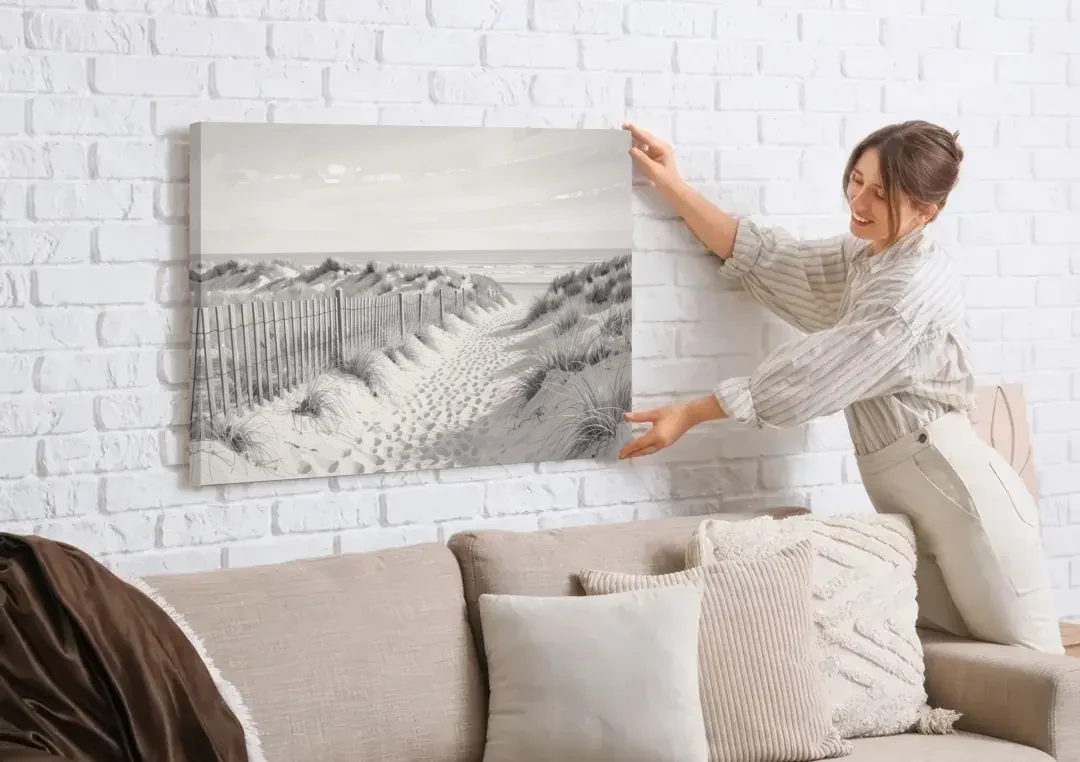 Coastal Black and White Dune Path to the Sea canvas wall art being hung on a white brick wall above a sofa