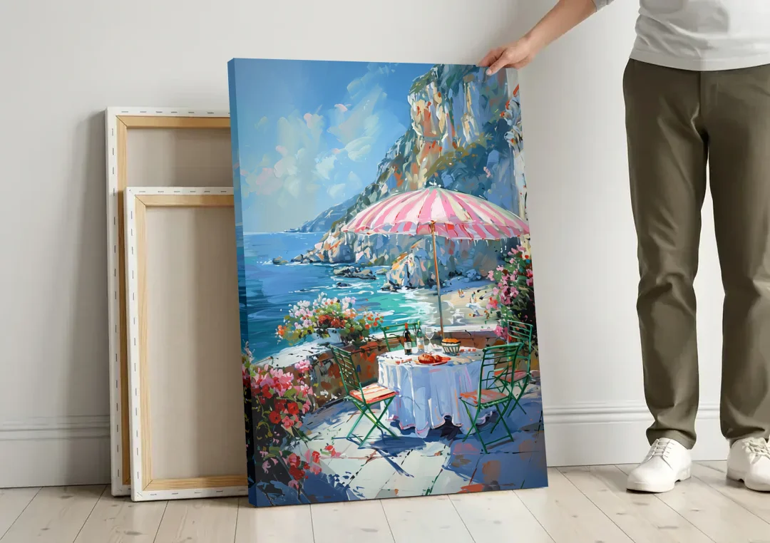 Coastal Painting with a Pink Striped Umbrella canvas wall art leaning against a wall next to blank canvases