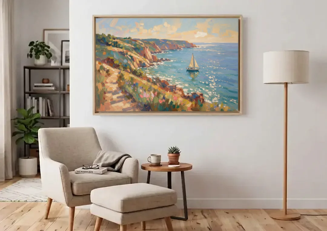 Coastal Wall Art Canvas of Sunlit Cliffs and Sailboat canvas wall art above an armchair in a bright living room
