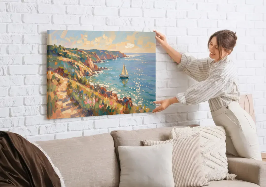 Coastal Wall Art Canvas of Sunlit Cliffs and Sailboat canvas wall art being hung on a white brick wall above a sofa
