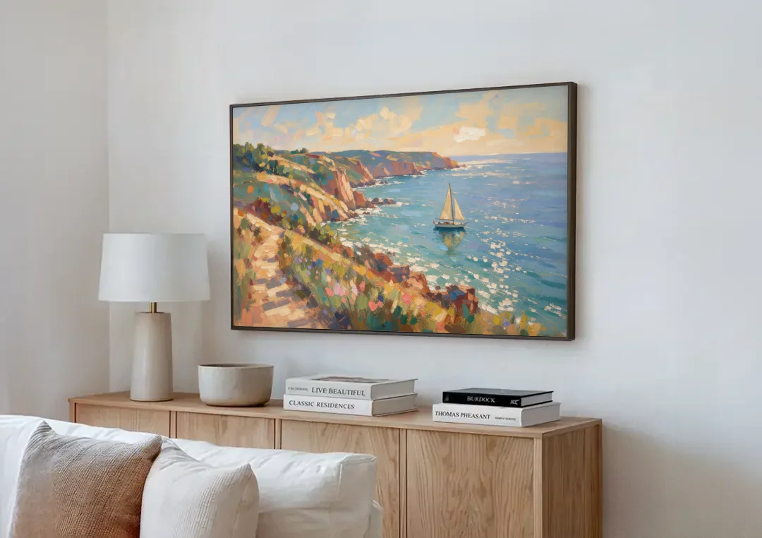 Coastal Wall Art Canvas of Sunlit Cliffs and Sailboat canvas wall art above a wooden sideboard next to a sofa