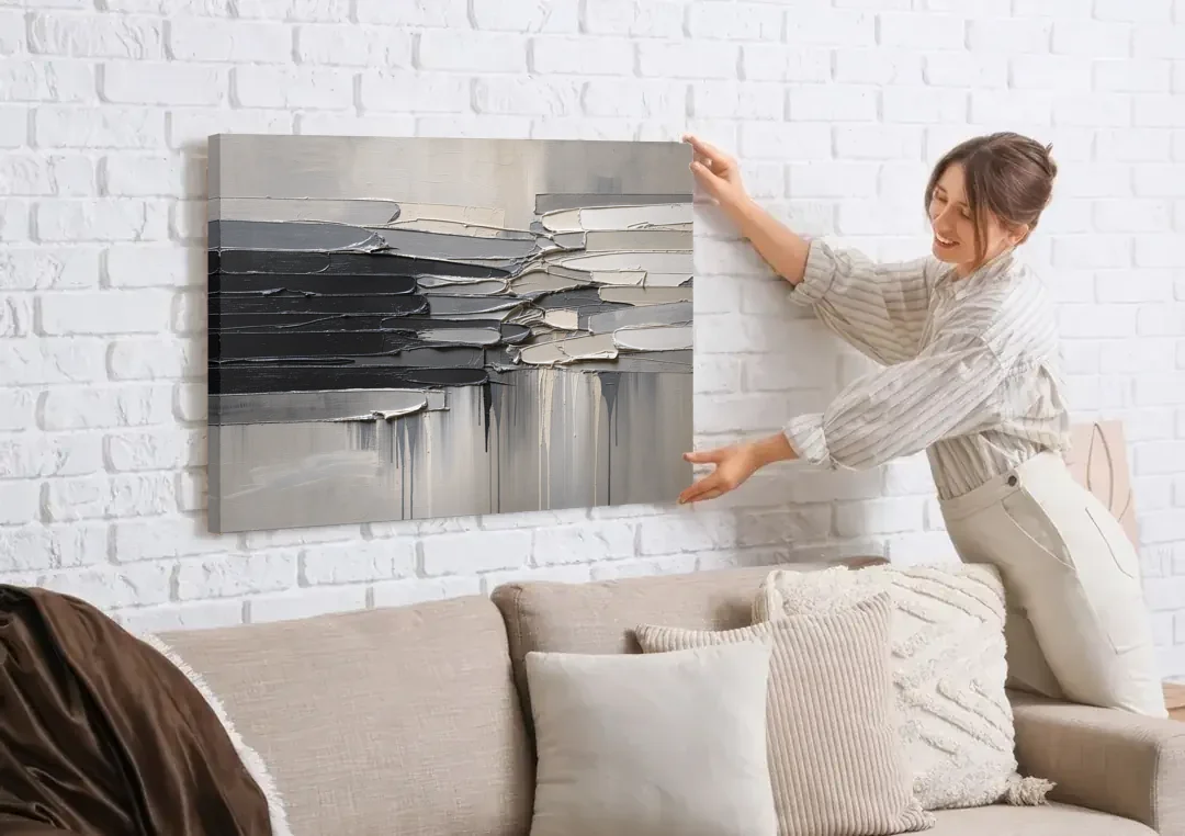 Contemporary Black and White Colliding Impasto Slabs canvas wall art being hung on a white brick wall above a sofa