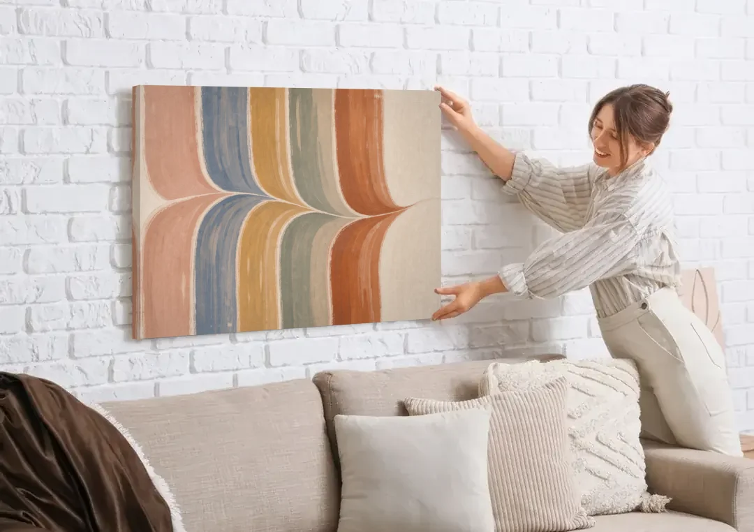 Colorful Boho Wall Art with a Gentle Stripe Wave canvas wall art being hung on a white brick wall above a sofa