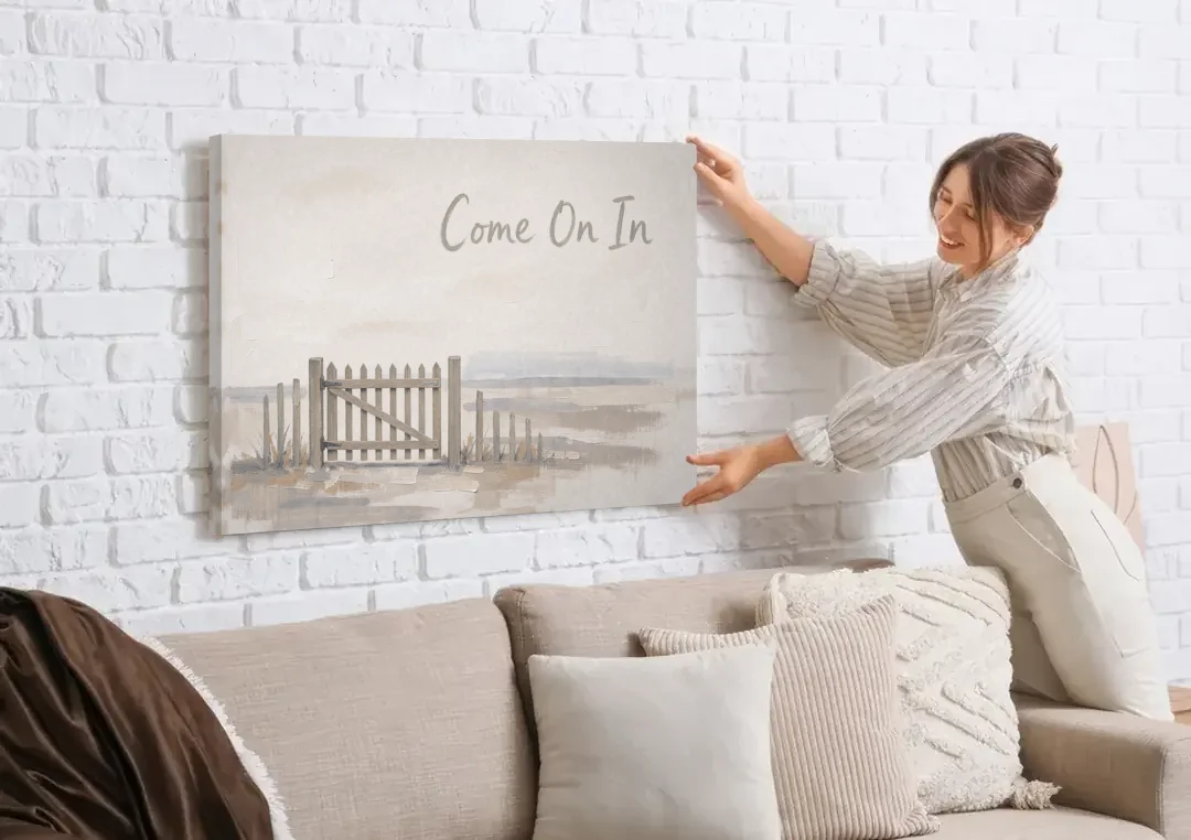 Come On In Garden Gate on a Cream Field canvas wall art being hung on a white brick wall above a sofa