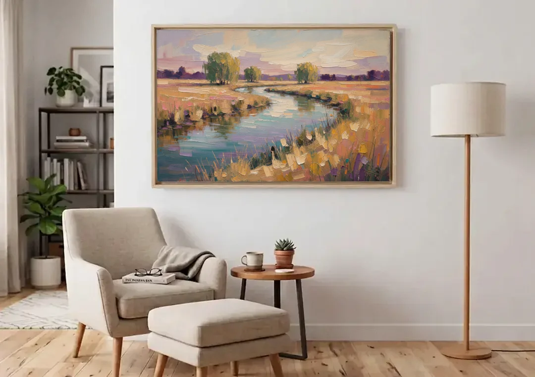 Creek Painting Winding Through a Summer Meadow canvas wall art above an armchair in a bright living room