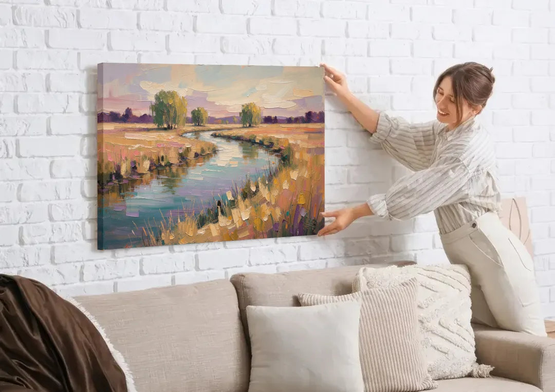 Creek Painting Winding Through a Summer Meadow canvas wall art being hung on a white brick wall above a sofa