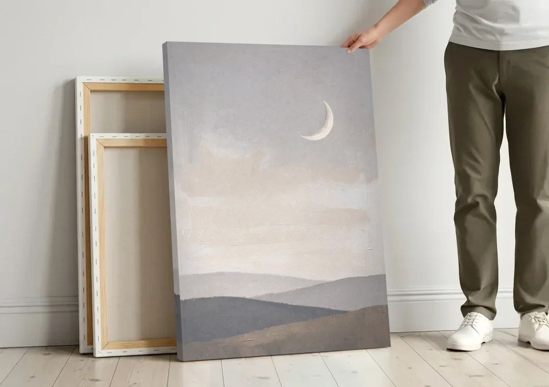 Crescent Moon Above Hazy Gray Hills canvas wall art leaning against a wall next to blank canvases