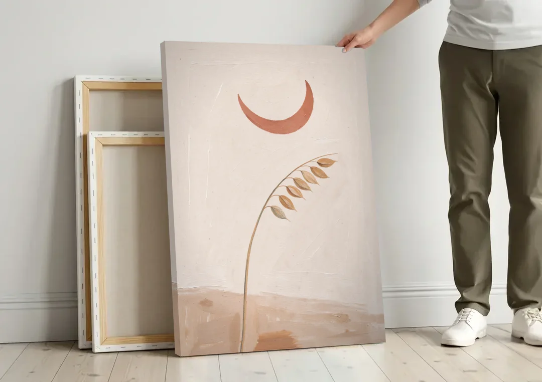 Crescent Moon Painting with a Bowing Grass Stem canvas wall art leaning against a wall next to blank canvases