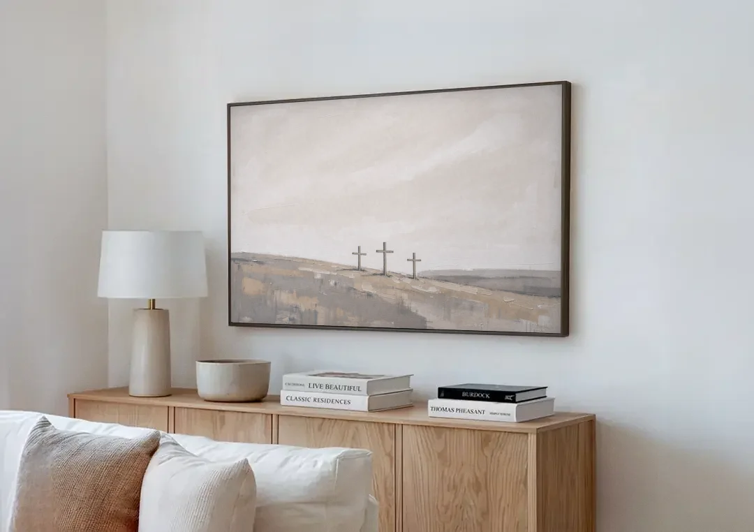 Cross Wall Art of Calvary Under a Quiet Sky canvas wall art above a wooden sideboard next to a sofa
