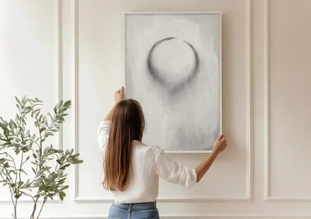 Minimalist Black and White Dissolving Charcoal Circle canvas wall art being hung on a paneled wall