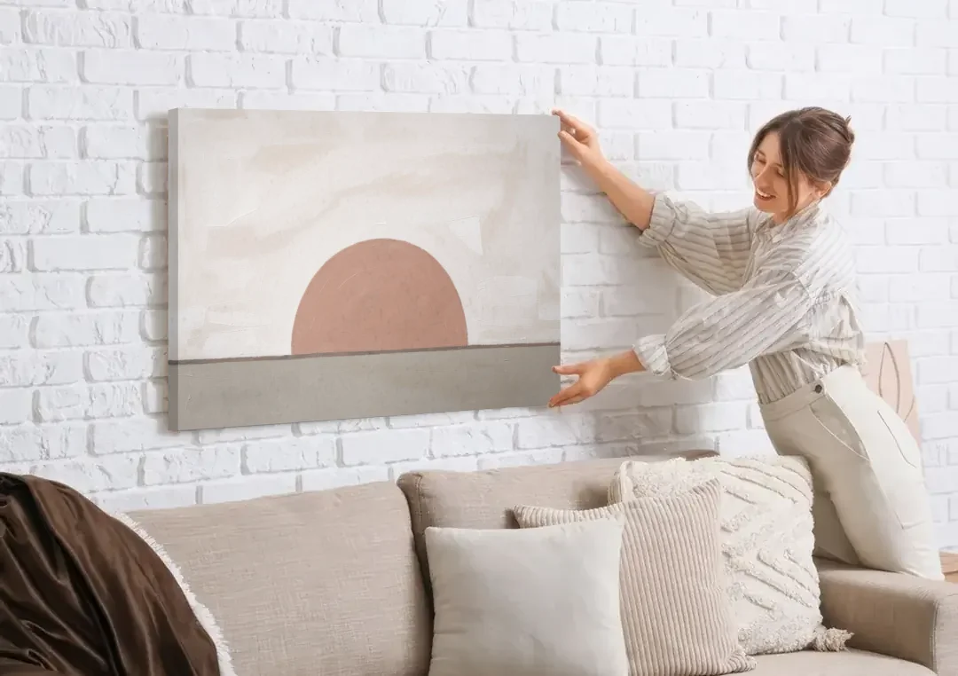 Earth Tone Abstract Art with Adobe Rose Half Sun canvas wall art being hung on a white brick wall above a sofa