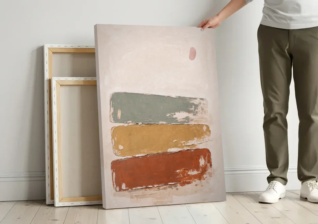 Earthy Abstract Painting with Blush Pebble canvas wall art leaning against a wall next to blank canvases