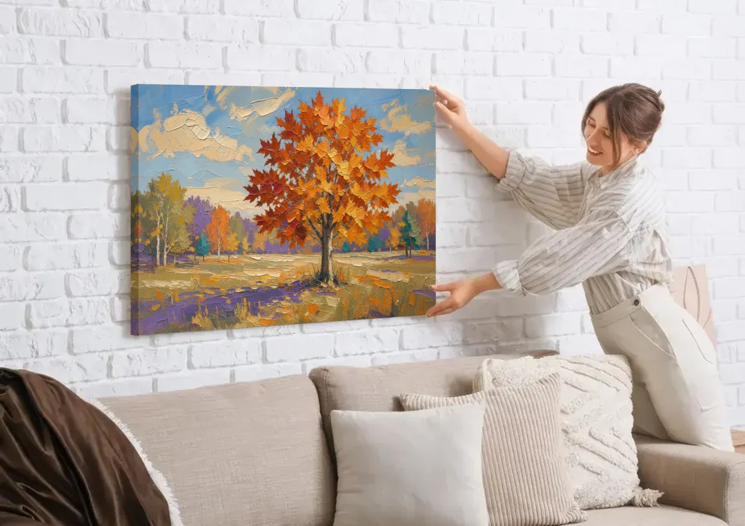 Fall Landscape Painting of a Blazing Maple canvas wall art being hung on a white brick wall above a sofa