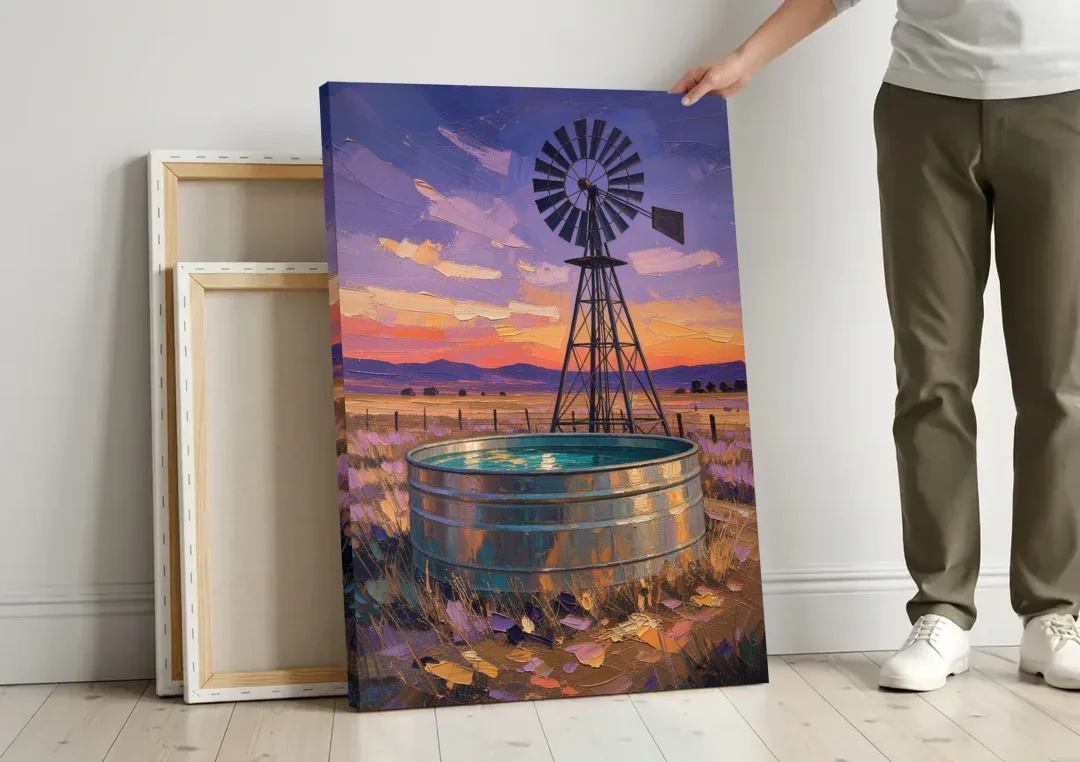 Farm Landscape Painting with Windmill and Stock Tank canvas wall art leaning against a wall next to blank canvases