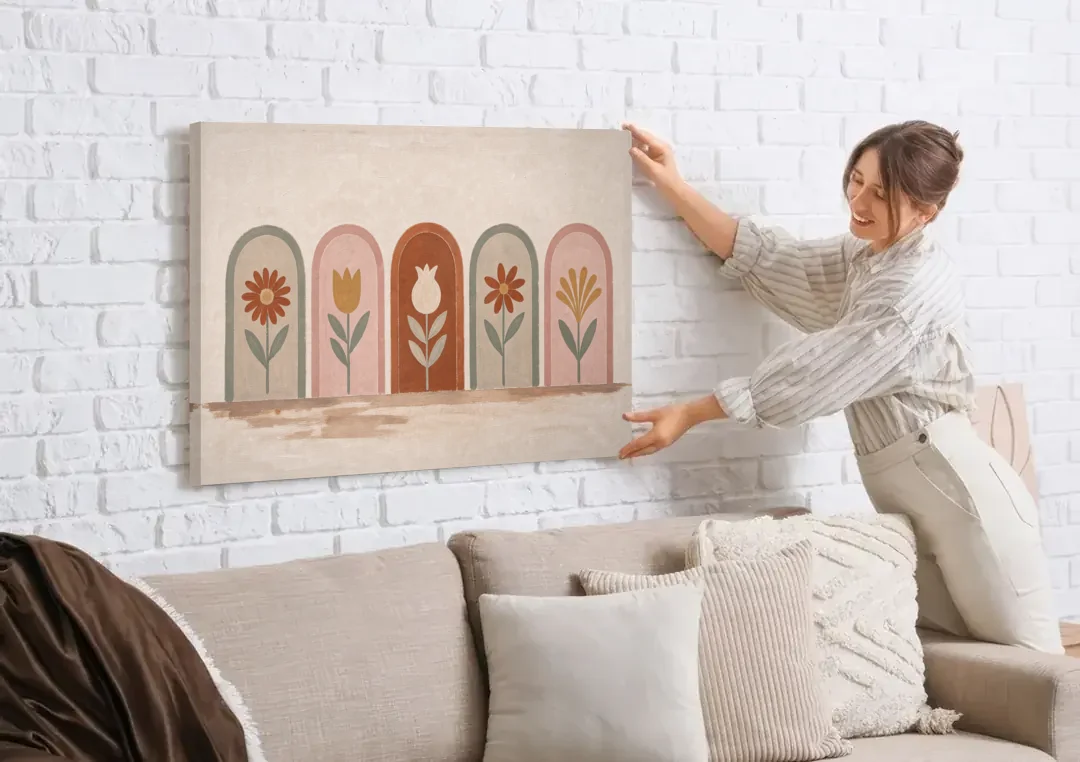 Folk Art Wall Decor with Five Flower Arches canvas wall art being hung on a white brick wall above a sofa