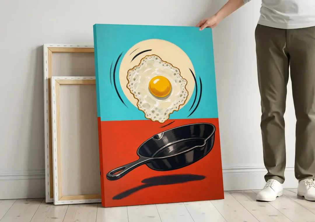 Funny Kitchen Wall Art with a Flipping Fried Egg canvas wall art leaning against a wall next to blank canvases