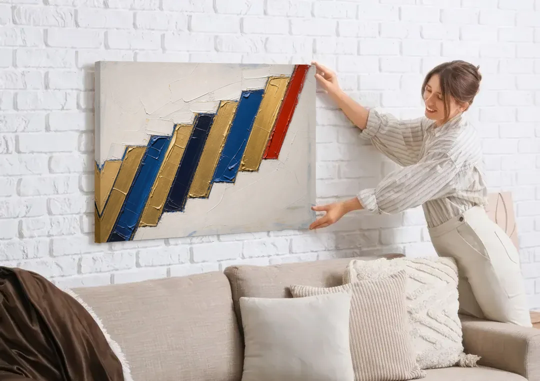 Geometric Abstract Wall Art in Cobalt and Gold Steps canvas wall art being hung on a white brick wall above a sofa