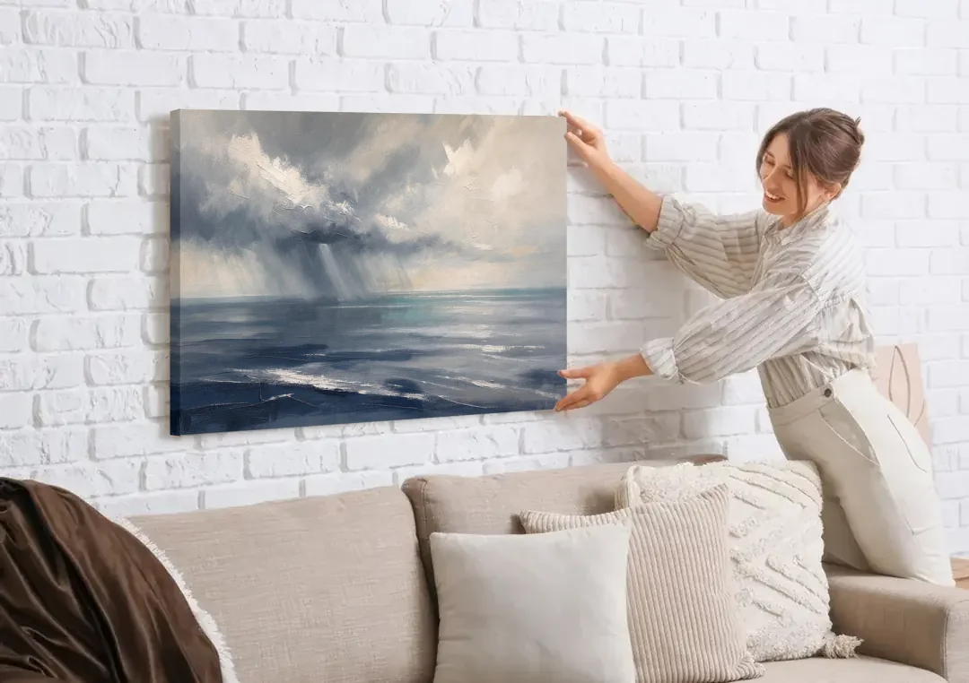 Gray and Blue Wall Art of a Sea Squall canvas wall art being hung on a white brick wall above a sofa