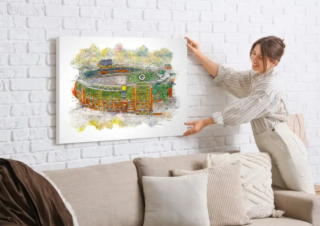 Green Bay Packers Lambeau Field Watercolor Stadium canvas wall art being hung on a white brick wall above a sofa
